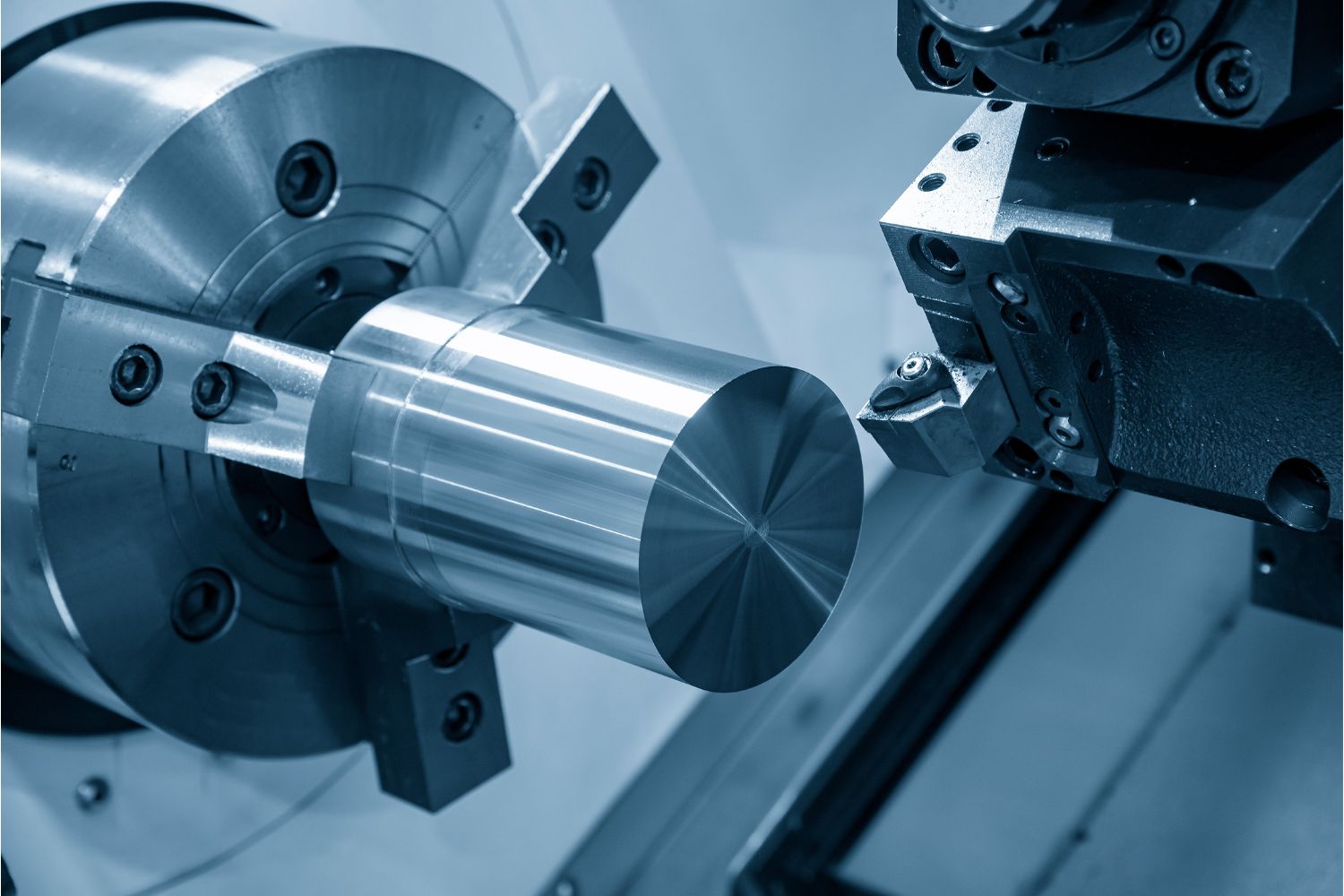 A metal cylinder attached to the lathe prepared to cut.